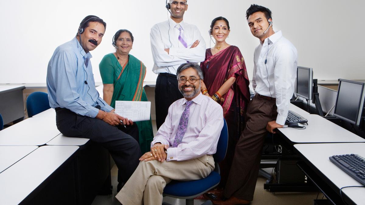 An office team wearing headsets, working at a bank of computer workstations