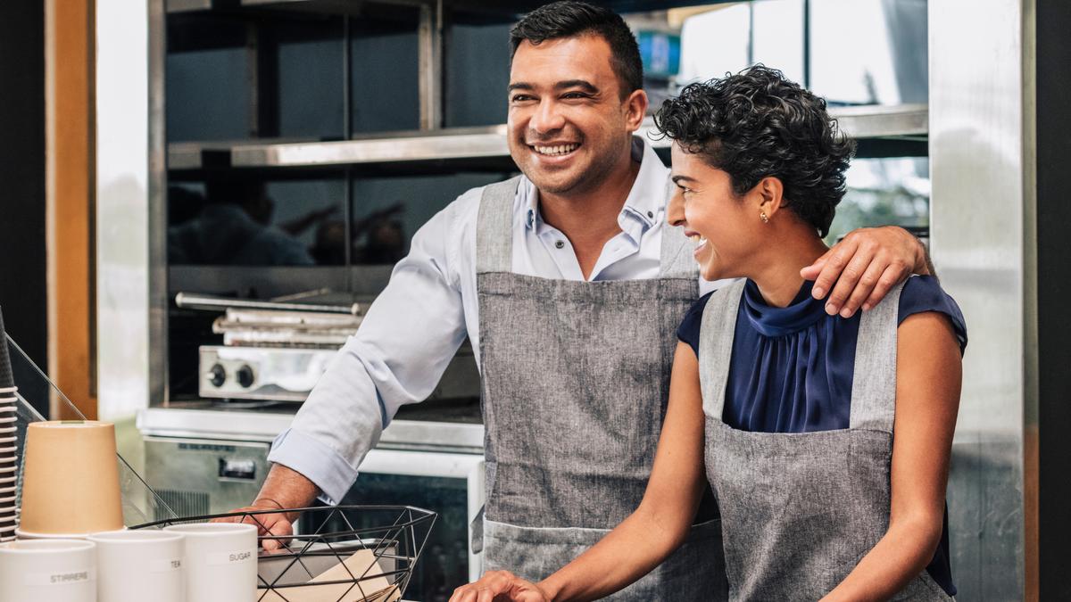 Two small business employees smiling together at their workplace, representing leave feeding into payroll