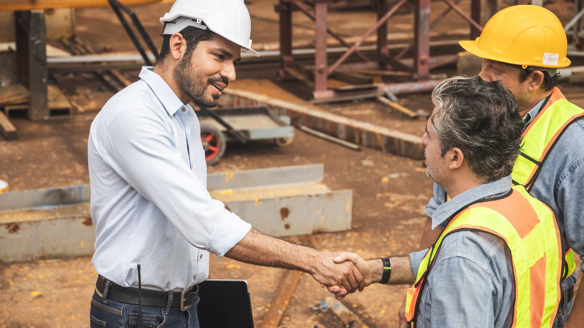 An Indian site manager shaking hands with construction workers, symbolizing full and final settlement