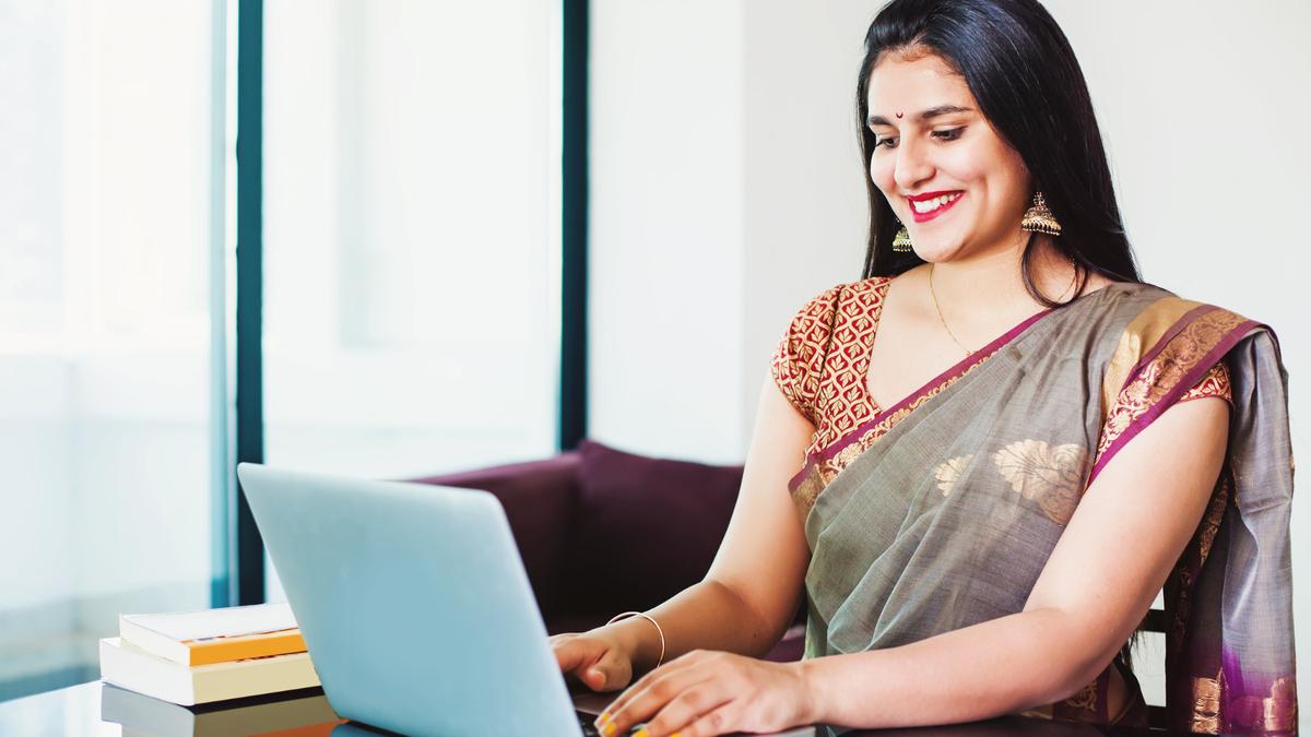 An Indian professional in a saree processing payroll on her laptop